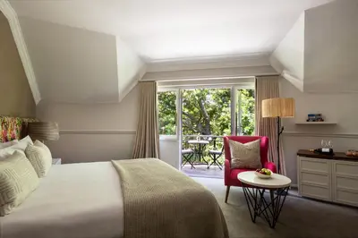 a bedroom with a bed and a chair and a window at Mont Rochelle Hotel and Vineyard in Franschhoek