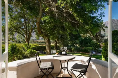 a table and chairs on a patio with trees at Mont Rochelle Hotel and Vineyard in Franschhoek