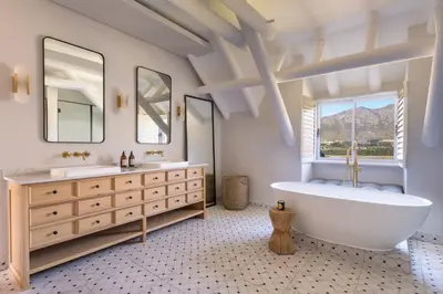 a bathroom with a tub and two sinks and a large window at Mont Rochelle Hotel and Vineyard in Franschhoek