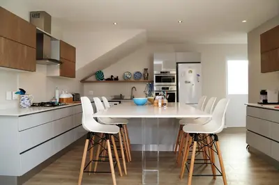 a kitchen with a large white table and stools at Cape Coral in Hermanus