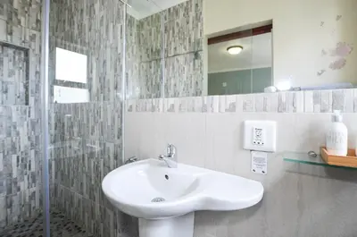 a bathroom with a sink and a glass shower at Atlantic Breeze in Cape Town