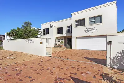 a white house with a garage and a brick driveway at Atlantic Breeze in Cape Town