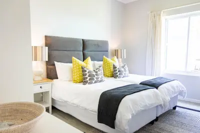 a bedroom with a large bed with yellow and gray pillows at On The Rocks in Hermanus