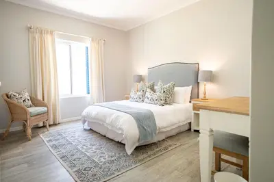 a bedroom with a bed and a desk and a window at On The Rocks in Hermanus