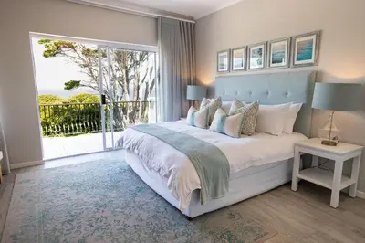 a bedroom with a large bed and a large window at On The Rocks in Hermanus