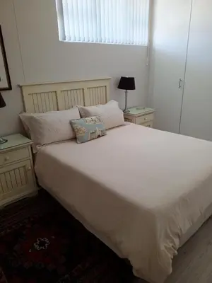a bedroom with a large white bed with two night stands at Beach front property in Strand