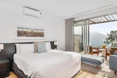 a bedroom with a white bed and a large window at Clouds Estate in Stellenbosch