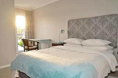 a bedroom with a bed and a table and a window at The Winelands Guest House in Bellville