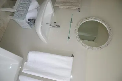 a white bathroom with a sink and a mirror at The Winelands Guest House in Bellville