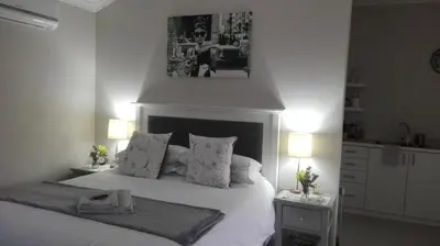 a bedroom with a large white bed with two lamps at Two Vines Romantic Guest Studio in Stellenbosch