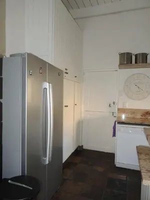 a kitchen with a stainless steel refrigerator and white cabinets at Brander View in Hermanus