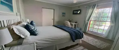 a bedroom with a large bed with a window at Dolphin Inn Blouberg in Bloubergstrand