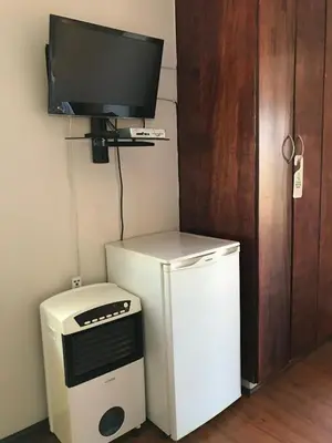 a television on a wall next to a small refrigerator at Hoogeind Manor in Somerset West