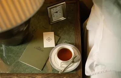a cup of coffee and a clock on a table at Maison Cabrière Boutique Hotel in Franschhoek