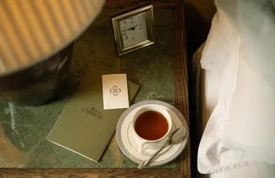 a cup of coffee on a table next to a clock at Maison Cabrière Boutique Hotel in Franschhoek