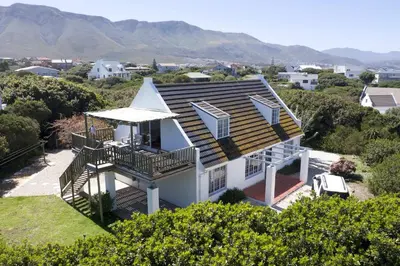a white house with a porch and a roof at Renovated Fishermans Cottage in Hermanus