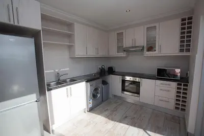 a kitchen with white cabinets and a washing machine at Lamabeach city farm in Cape Town