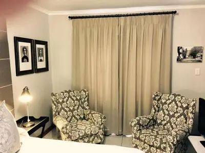a hotel room with two chairs and a bed at Centre-Ville Guest House in Franschhoek