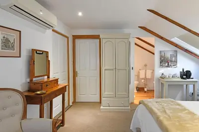 a bedroom with a bed and a vanity and a mirror at Centre-Ville Guest House in Franschhoek