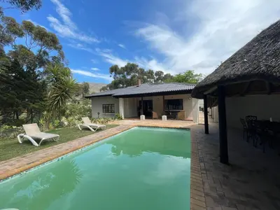 a swimming pool in front of a house at Swaynekloof Farm in Botrivier