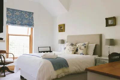 a bedroom with a bed and a desk and a window at The Victorian Goose in Cape Town