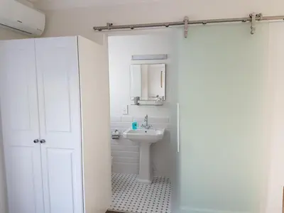 a white bathroom with a sink and a mirror at The Victorian Goose in Cape Town