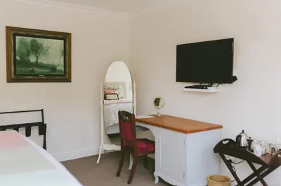 a bedroom with a desk with a television and a bed at The Victorian Goose in Cape Town