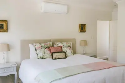 a bedroom with a white bed with pillows on it at The Victorian Goose in Cape Town