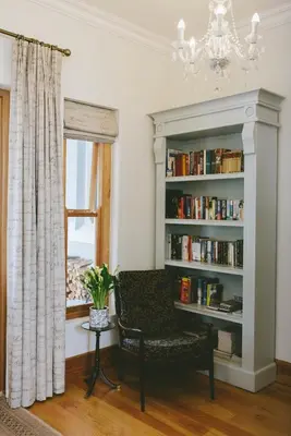 a living room with a chair and a book shelf at The Victorian Goose in Cape Town
