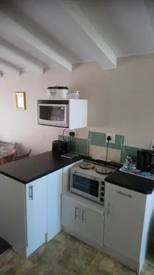 a kitchen with white cabinets and a stove top oven at Welterusten Guesthouse in Strand