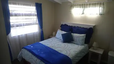 a bedroom with a bed with blue sheets and a window at Welterusten Guesthouse in Strand