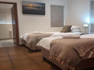 a bedroom with two beds and a picture on the wall at Paddabult Self Catering Cottages in Paarl