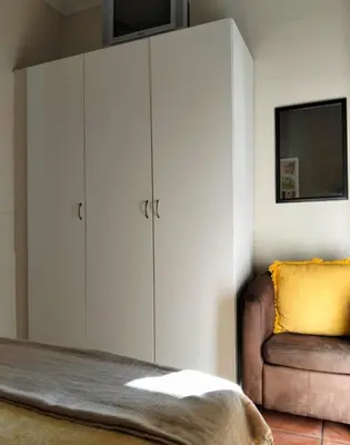 a bedroom with a bed and a chair and cabinets at Glen Lilly Self Catering in Parow
