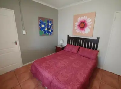 a bedroom with a bed with a red bedspread at N-One Self Catering in Goodwood