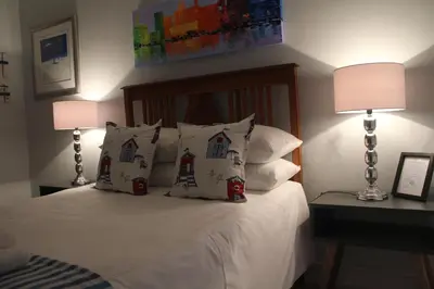 a bedroom with a bed with pillows and two lamps at Merci Pére in Gordonʼs Bay