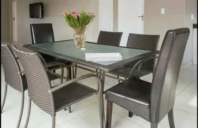 a dining room table with chairs and a vase with flowers at Milnerton Guesthouse in Cape Town