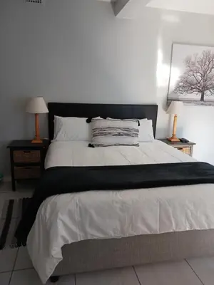 a bedroom with a large white bed with two lamps at The Palm in Pinelands in Cape Town