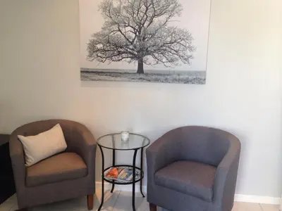 two chairs and a table in a room with a tree at The Palm in Pinelands in Cape Town