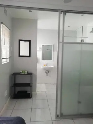 a bathroom with a glass shower and a sink at The Palm in Pinelands in Cape Town
