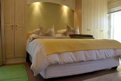 a bedroom with a bed with white sheets and pillows at Somerset West Self Catering Vacation Rental - Experience the Best of Cape Town - Wine, Golf, Sea in Somerset West