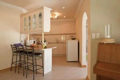 a kitchen with a bar with stools and a refrigerator at Somerset West Self Catering Vacation Rental - Experience the Best of Cape Town - Wine, Golf, Sea in Somerset West
