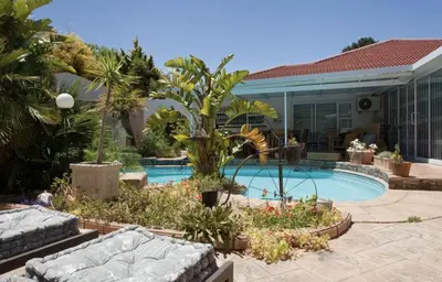 a swimming pool in a yard with a house at Somerset West Self Catering Vacation Rental - Experience the Best of Cape Town - Wine, Golf, Sea in Somerset West