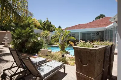 a patio with a chair and a swimming pool at Somerset West Self Catering Vacation Rental - Experience the Best of Cape Town - Wine, Golf, Sea in Somerset West