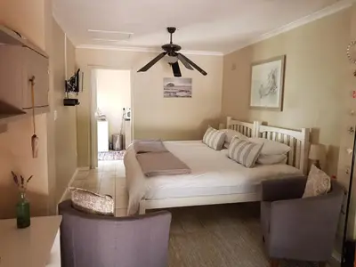 a bedroom with a white bed and a ceiling fan at The Fairway in Cape Town