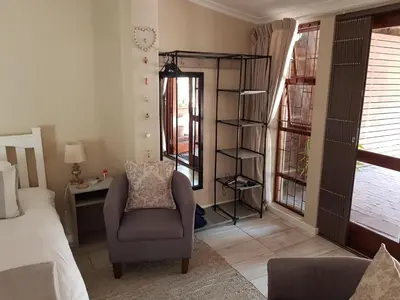 a bedroom with a chair and a room with windows at The Fairway in Cape Town