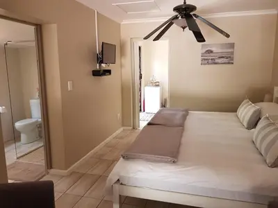 a bedroom with a bed and a ceiling fan at The Fairway in Cape Town