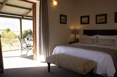 a bedroom with a bed and a sliding glass door at Zebra Cottage and Lodge in Stellenbosch
