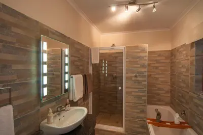 a bathroom with a sink and a shower and a tub at Wind-Rose Guest House in Gordonʼs Bay