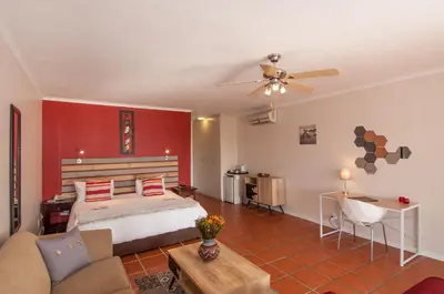 a bedroom with a bed with a red wall at Wind-Rose Guest House in Gordonʼs Bay