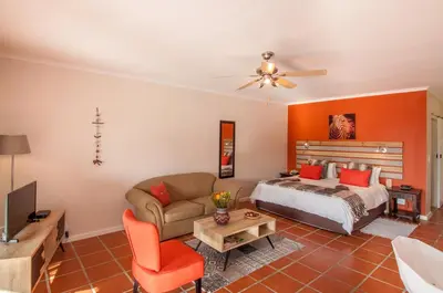 a living room with a bed and a couch at Wind-Rose Guest House in Gordonʼs Bay